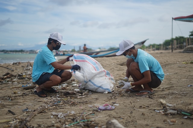 2 volunteers on a beach picking up trash